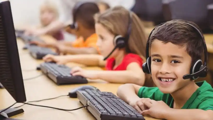 Children in a classroom, each working at a PC.